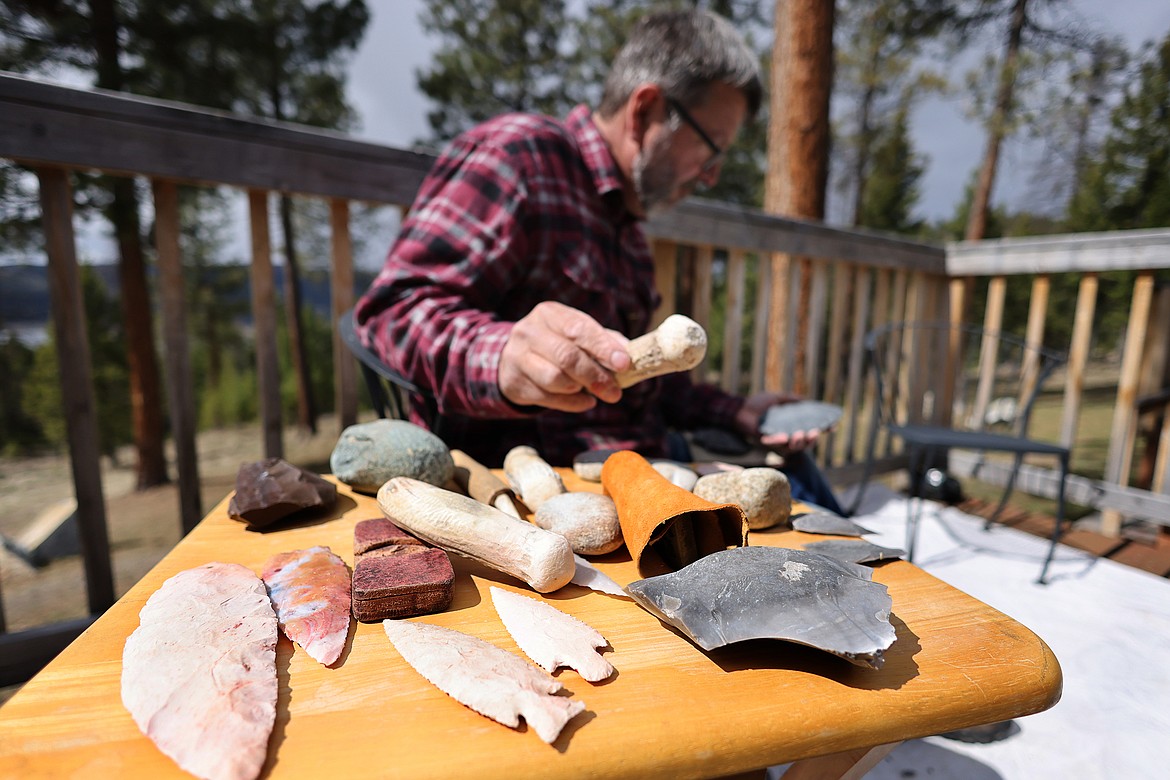 Tom Blais reaches for one of his bone tools while working to create a stone knife. (Jeremy Weber/Daily Inter Lake)