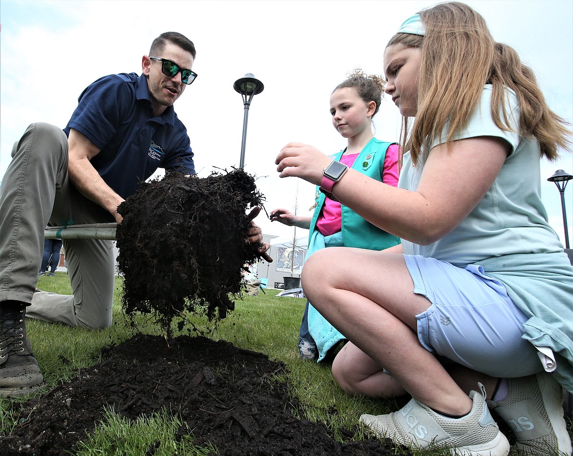 City of Coeur d'Alene Urban Forester Nick Goodwin works with students Penny Bircher, left, and Oakley Wagner on planting trees at the East Sherman Pocket Park on Friday.