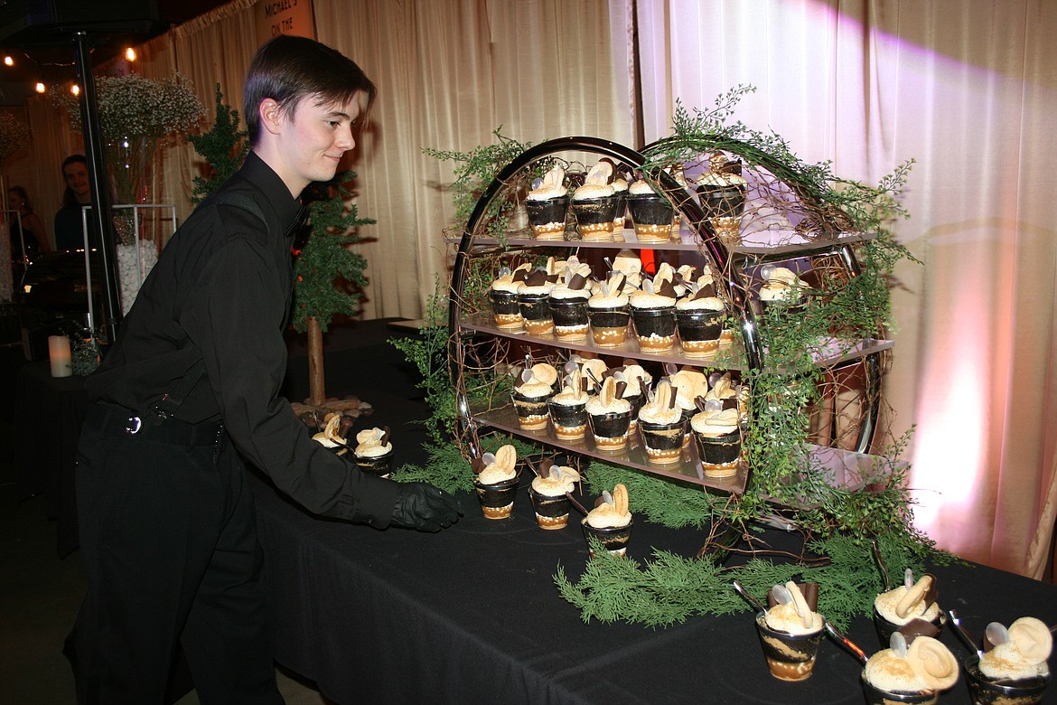 Jagger Hansen of the Rock Top Burgers & Brew prepares a cupcake display prior to Bourbon & Bowties Friday at the Grant County Fairgrounds.