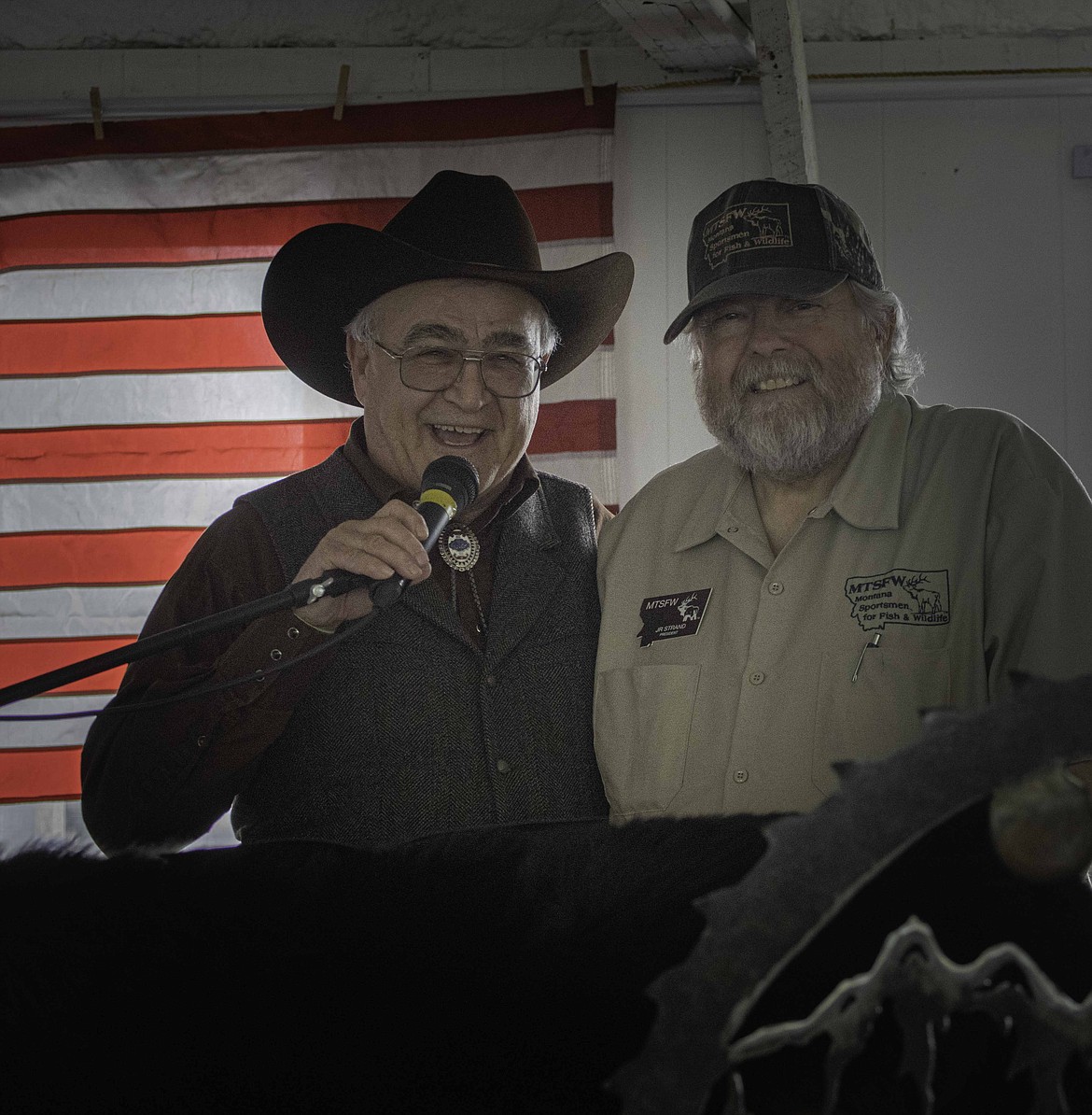 Auctioneer Dwight Gappert gets ready for the live auction at the Montana Sportsmen For Wildlife Pig Roast Fundraiser, as J.R Strand, President, beams with joy at the turnout. (Tracy Scott/Mineral Independent)