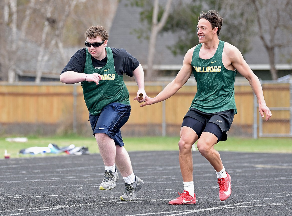 Donovan Lindquist gets the baton from Ryder Barinowski in the 4X100 unified relay race on Saturday. (Whitney England/Whitefish Pilot)