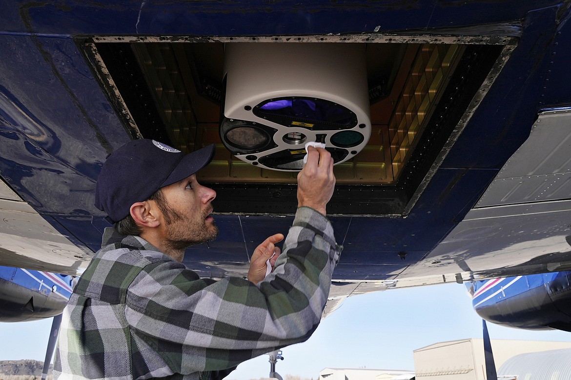 Dan Berisford, an engineer with Airborne Snow Observatories, cleans a laser mapping device used to measure snow that is mounted under an airplane, Monday, April 18, 2022, in Gunnison, Colo. Some drought-prone communities in the U.S. West are mapping snow by air to refine their water forecasts. (AP Photo/Brittany Peterson)