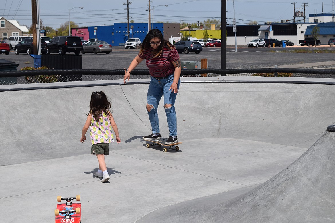 Maricella Wade skates in the new concrete addition to the Moses Lake Skate Park while her daughter Ofelia, three, looks on.