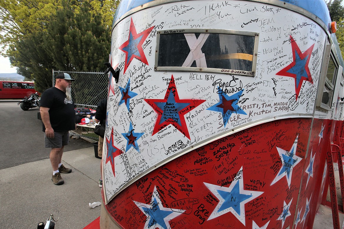 Dennis Davies of Helena, Mont., chats with a visitor of his patriotic trailer at The People's Convoy rally at Stateline Speedway on Wednesday.