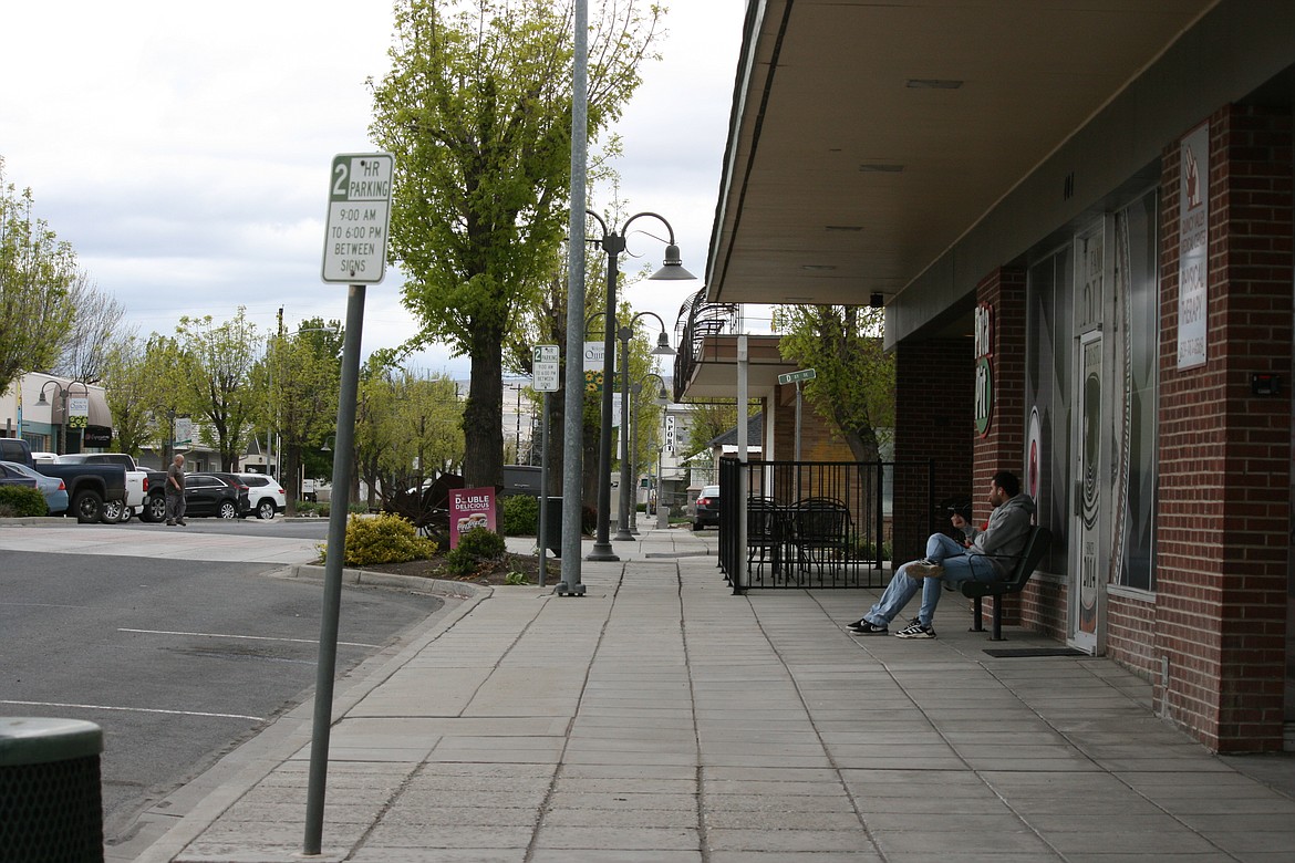 Shoppers occupy a bench in downtown Quincy Friday afternoon. Downtown is the focus of a revitalization plan that will be the subject of a public hearing at the May 17 Quincy City Council meeting.