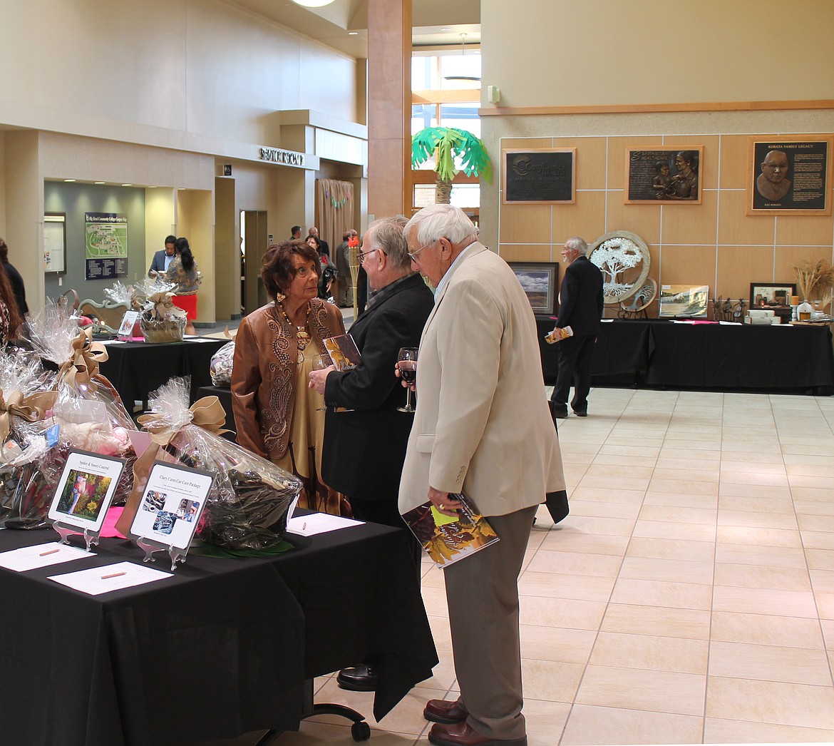 From left, Cheri Smith, Jack McLauchlan and Ed Smith check out the silent auction offerings at Cellarbration! For Education this past Saturday evening.