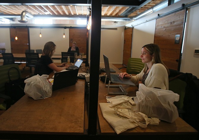 Charlotte Doutriaux, right, works on her laptop in a co-working space in the Innovation Den.