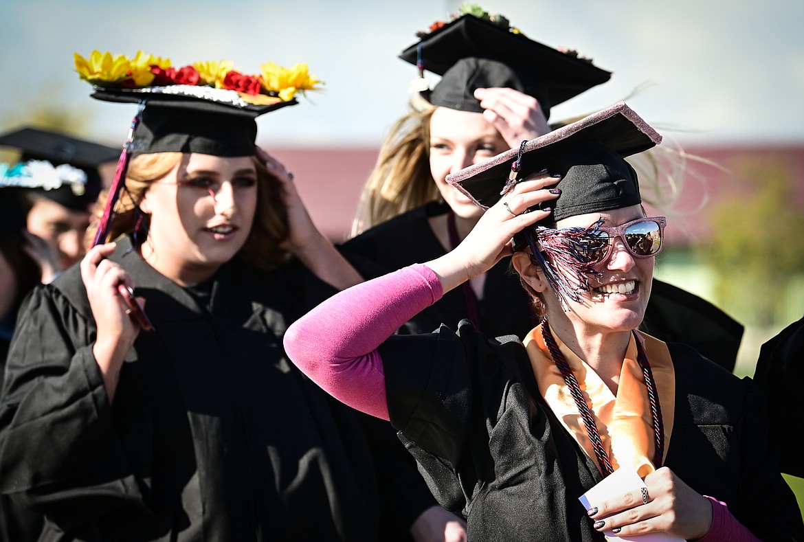 Graduates hold on to their mortarboards and tassels as the wind whips across campus at the Flathead Valley Community College Class of 2022 commencement ceremony on Friday, May 13. A total of 304 graduates earned 319 degrees and certificates (Casey Kreider/Daily Inter Lake)