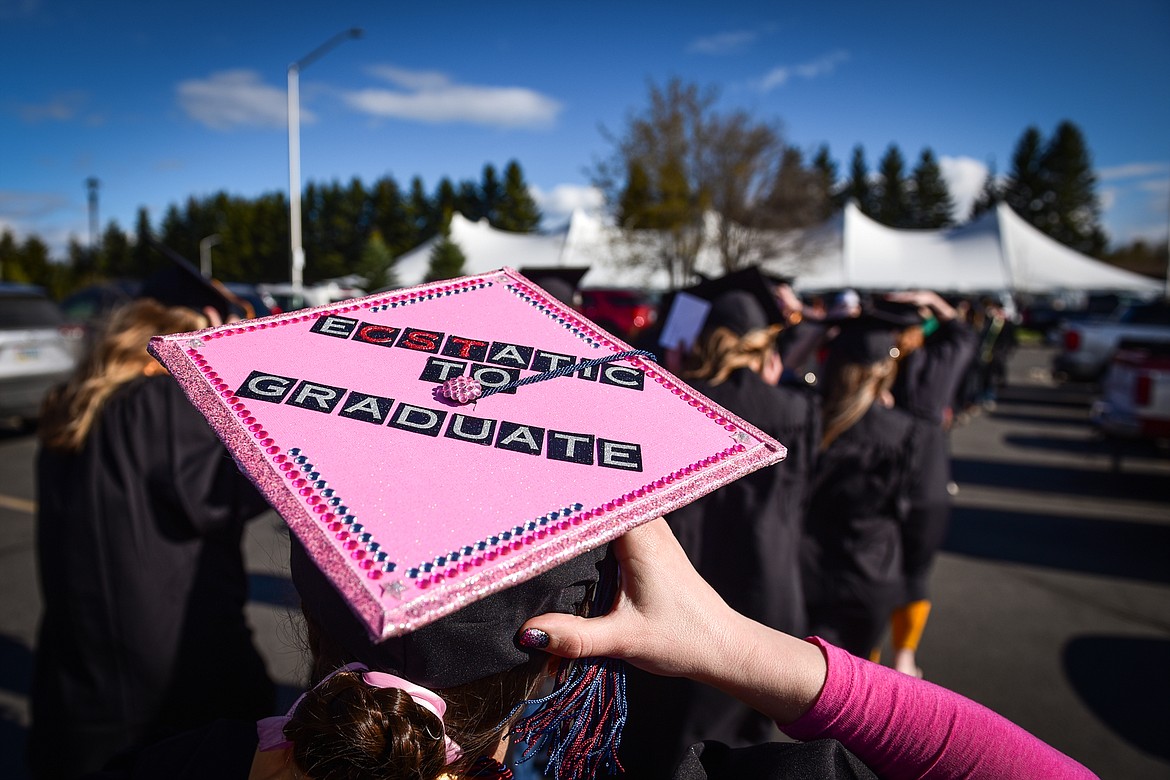 A graduate holds on to a decorative mortarboard as the wind whips across campus at the Flathead Valley Community College Class of 2022 commencement ceremony on Friday, May 13. A total of 304 graduates earned 319 degrees and certificates (Casey Kreider/Daily Inter Lake)
