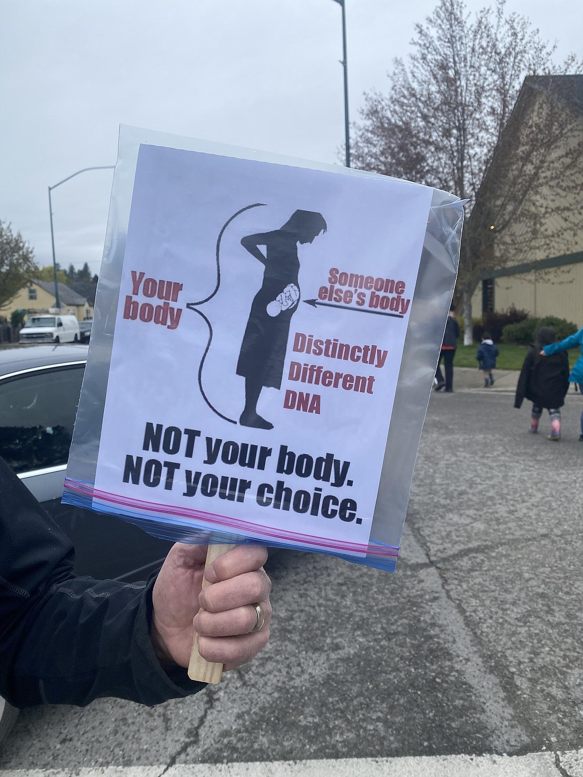 A silent protester stands along the route of the Kootenai County Women's March Saturday.