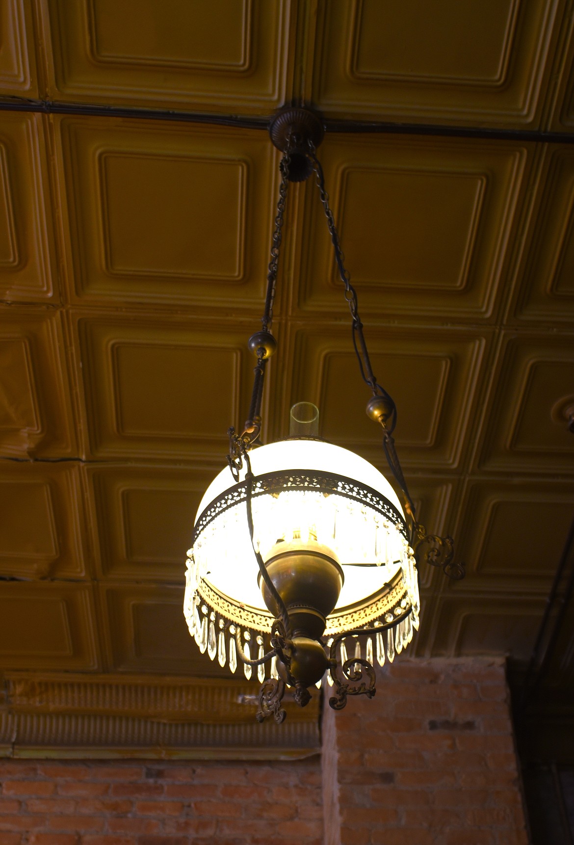 A vintage ceiling light hangs near the bathroom area. The stamped tin tiles are original to the building and were hidden by the previous ceiling. (Scot Heisel/Lake County Leader)