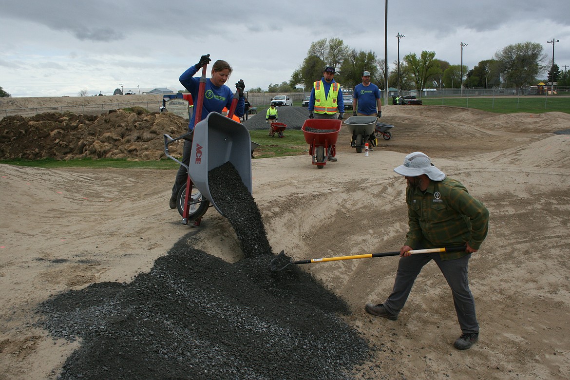 Julie Ellington (left), a volunteer with the Evergreen Mountain Bike Alliance, dumps rock on Quincy's new pump track. Designer Shawn Lorenz spreads the rock as it’s dumped.