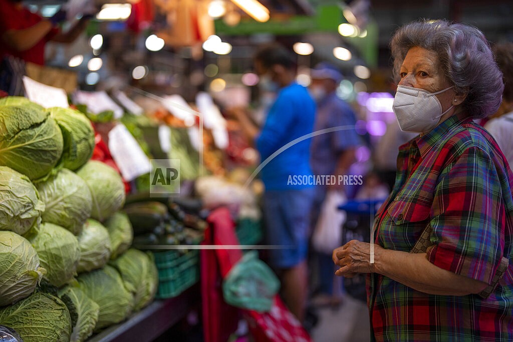A customer wearing a face mask waits to buy vegetables at the Maravillas market in Madrid, Thursday, May 12, 2022. Russia's war in Ukraine has accelerated inflation across Europe, with prices for energy, materials and food surging at rates not seen for decades. Inflation is expected to hit nearly 7% this year in the 27-nation EU and is contributing to slowing growth forecasts. (AP Photo/Manu Fernandez)