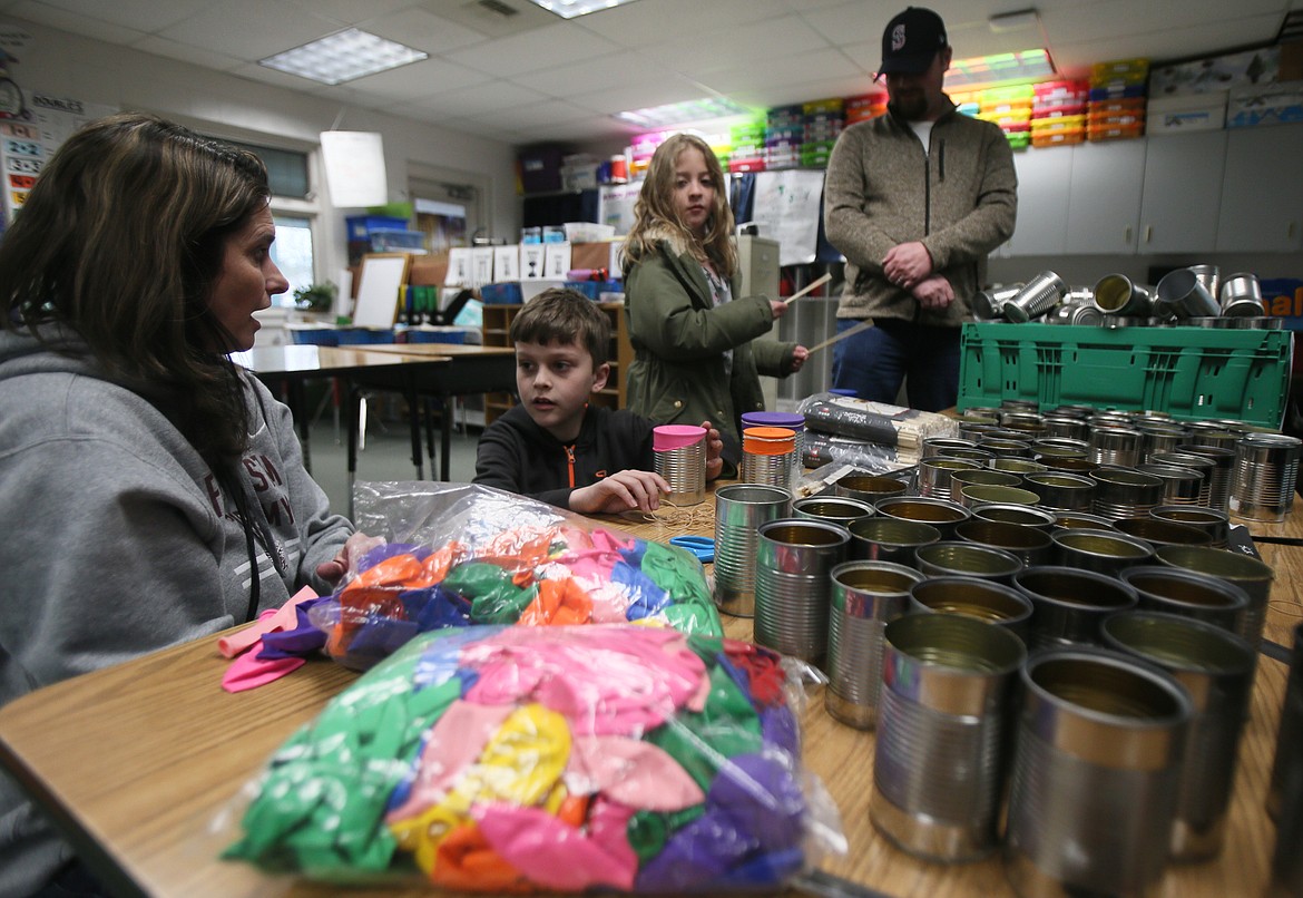 Speech therapist Beth James helps Fernan STEM Academy fourth-grader Zaine Garrett make a drum out of a can and a balloon. His sister, Madi, and dad, Daniel, are also pictured.
