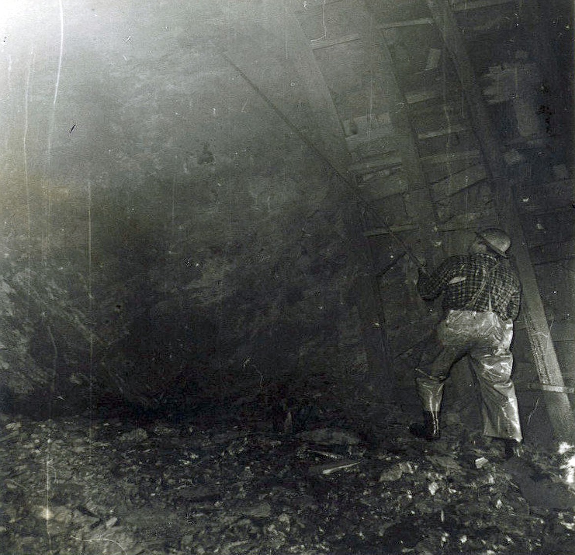 A "picker" checking the ceiling for weaknesses after a round of blasting during the construction of the Flathead Tunnel. The worker was later killed by a falling rock. (Bruce Morse photo)
