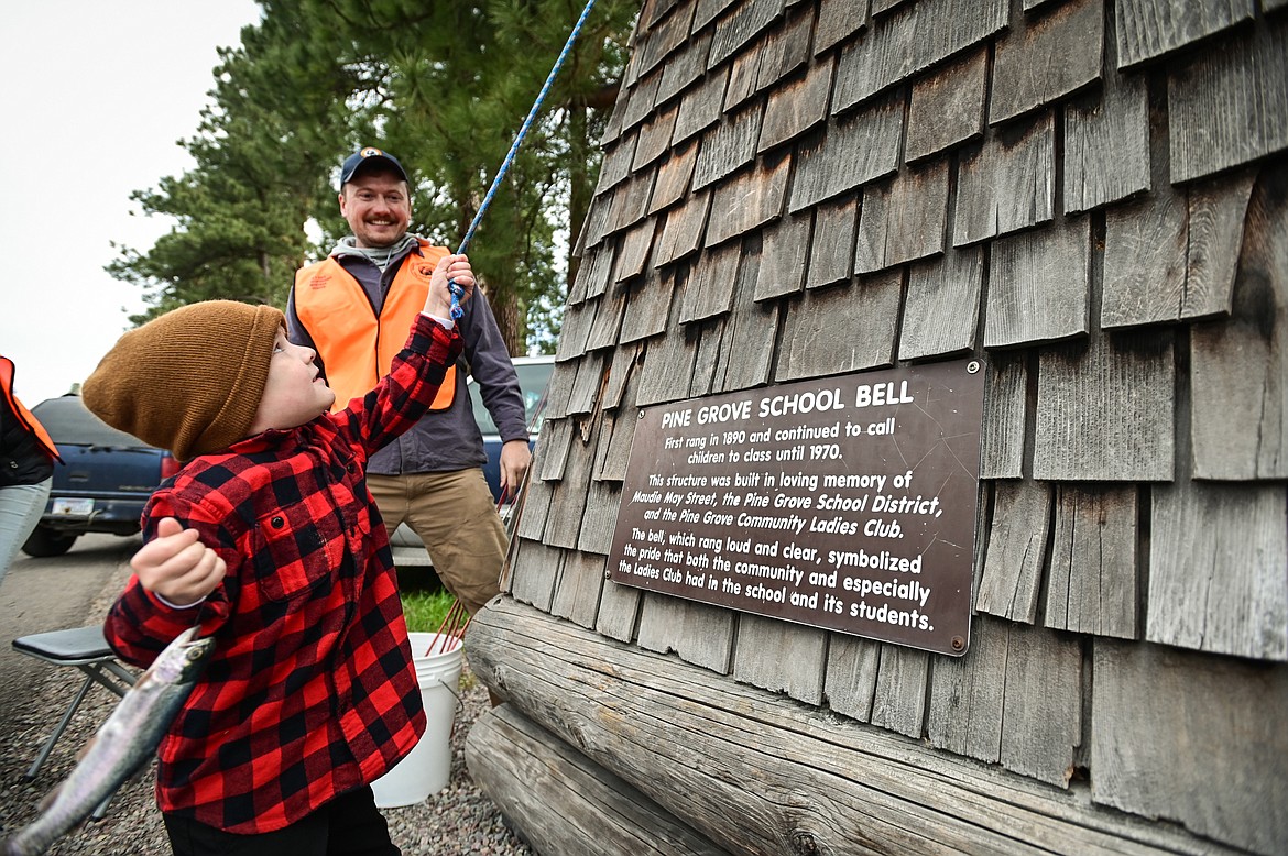 Blu Meehan rings the Pine Grove School bell while holding the first fish he has ever caught at the Brooke Hanson Memorial Family Fishing Day at Pine Grove Pond on Saturday, May 21. Behind Meehan is Dillon Tabish, Regional Communication and Education Program Manager with Montana Fish, Wildlife & Parks. Hundreds of prizes were donated by area merchants and sportsmen's groups to be awarded to kids 12 and under. The event was sponsored by Flathead Wildlife and donations go to enhancing fishing opportunities around the Flathead in Brooke Hanson's memory. (Casey Kreider/Daily Inter Lake)