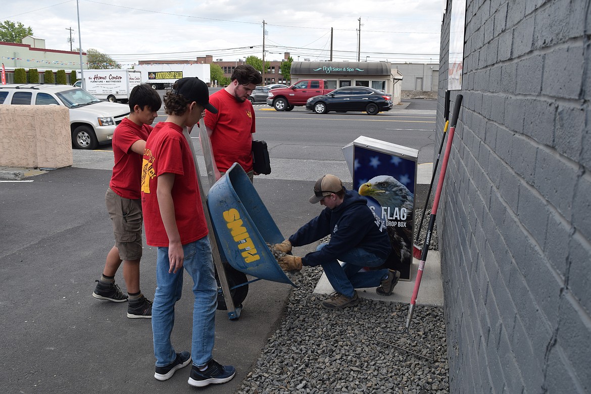 Eagle Scout Garrett Smith (center, with clipboard) supervises fellow Troop 0069 scouts Nathaniel Bradley (holding the wheelbarrow), Thomas Howard (front) and Braden Helvy (kneeling, scooping out gravel) as they finish installing a flag drop box in the parking lot of American Legion Joe R. Hooper Post 209 in Moses Lake on Thursday.