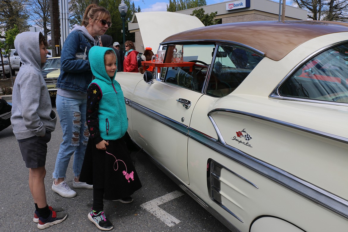Jayme, Caleb and Cassidy Belville of Sandpoint look at a car made to look as if it is at an A&W drive-in as they look at the cars taking part in the Lost in the '50s car show.