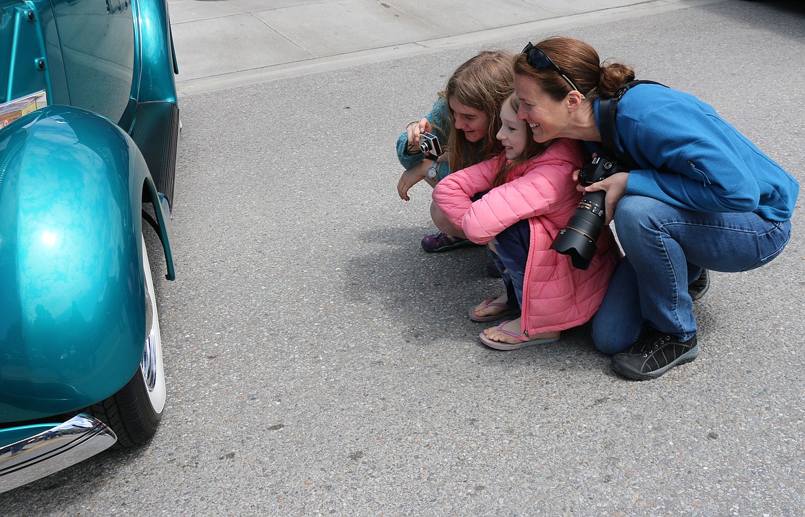 The Coleman family from Sagle check out their reflection in the hubcap of a classic car during the Lost in the '50s car show in downtown Sandpoint on Saturday.