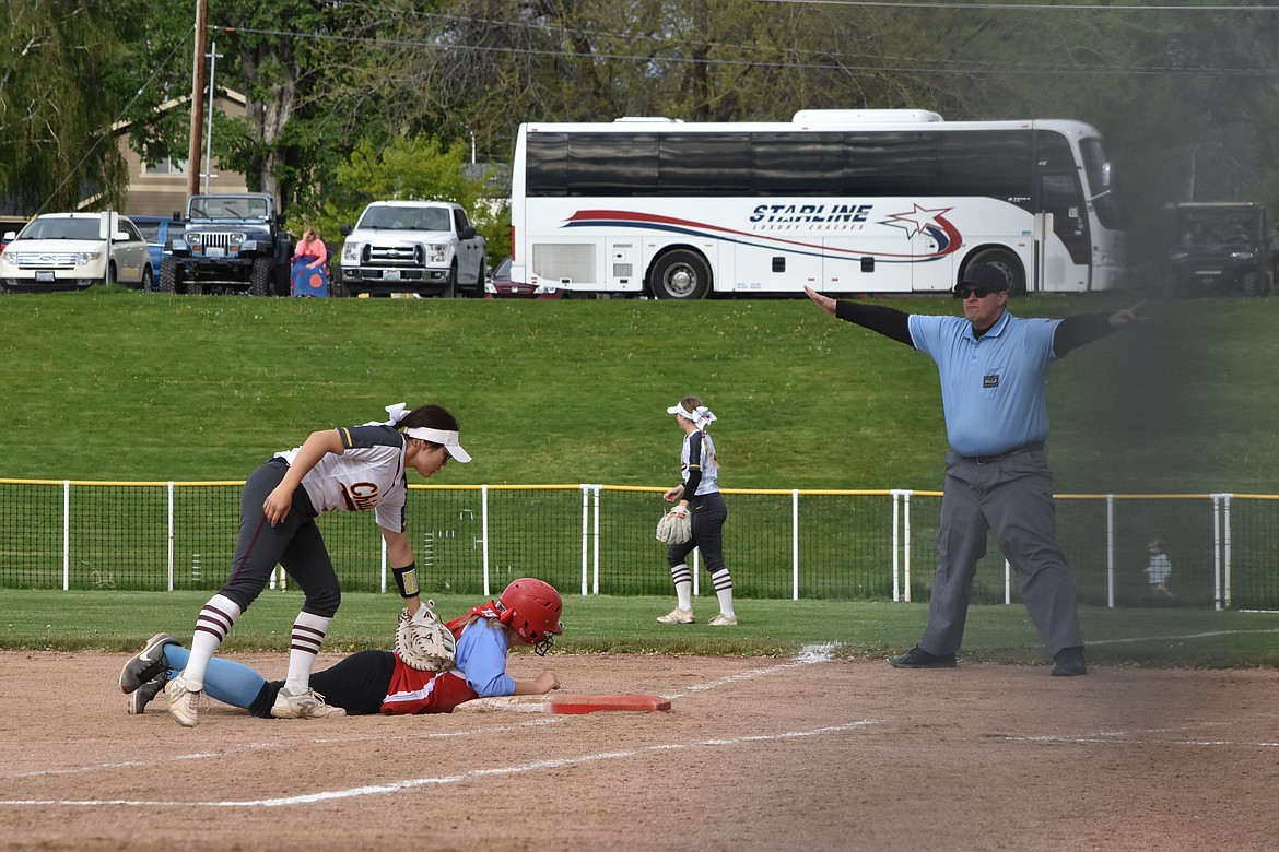 Moses Lake senior Rylie Sanchez (12) tags an Eastmont player who slides back to first base during the district matchup on Friday. The referee can be seen calling the Eastmont player safe.