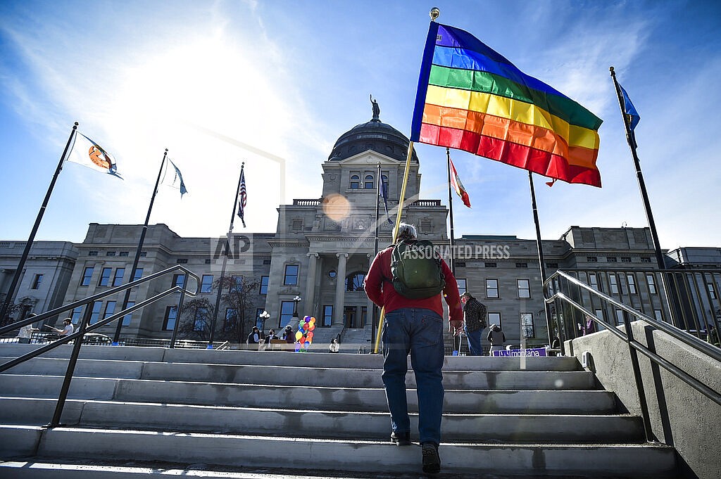 In this March 15, 2021, file photo, demonstrators gather on the steps of the Montana State Capitol protesting anti-LGBTQ+ legislation in Helena, Mont. It's been a month since a Montana judge temporarily blocked enforcement of a state law that required transgender people to undergo surgery before they could change their gender on their birth certificate, and the state still isn't in compliance with the court order, the ACLU of Montana said. (Thom Bridge/Independent Record via AP, File)