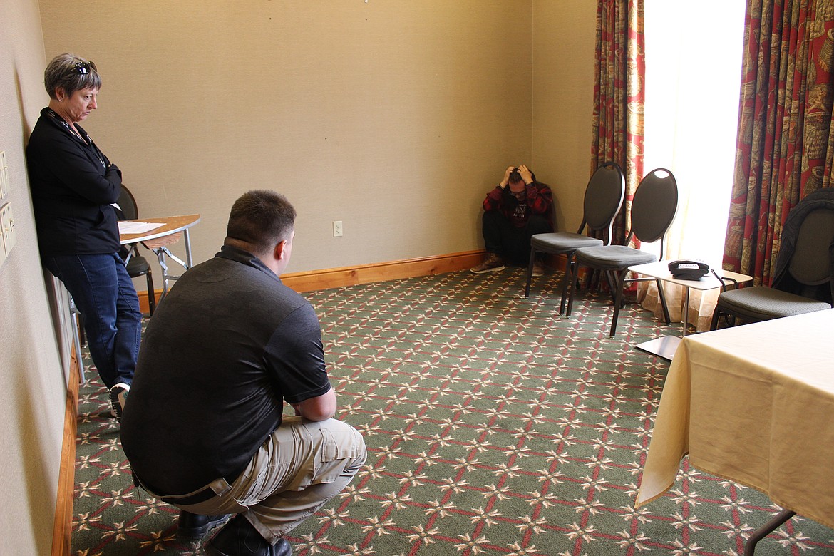 CIT Coordinator Clair Swain, Joe Bakker, with the Bigfork Fire Department, and Flathead Valley Community College acting student Sean Struble work through a scenario during a Montana Crisis Intervention Training event at the Hilton Garden Inn. Struble is acting as a person with schizophrenia who is having a breakdown while he is being detained in jail. (Taylor Inman/Bigfork Eagle)