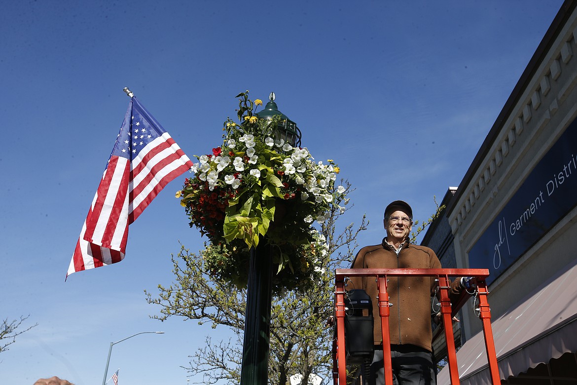 Bill Reagan, president of The Coeur d'Alene Resort, looks toward the next light post after putting up a flower basket on Sherman Avenue on Thursday.