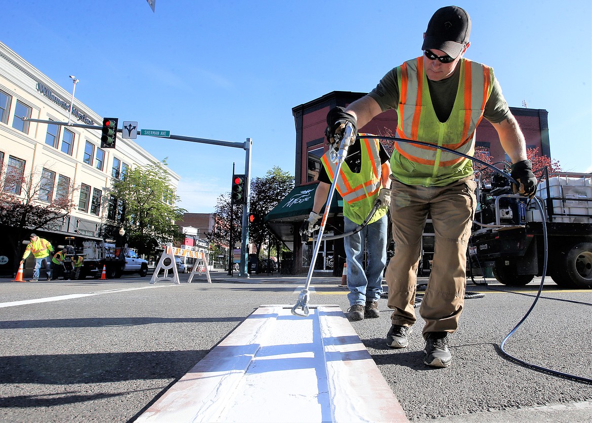 Travis Galloway with the city of Coeur d'Alene paints new crosswalk stripes on Sherman Avenue on Thursday morning. The city paints the downtown area crosswalks before Memorial Day, and the city's remaining crosswalks throughout the summer.