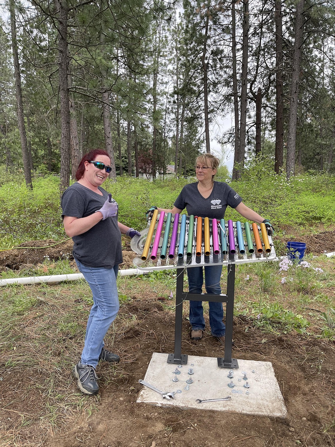 Mountain West Bank employees Toni McCurdy (left) and Jodi Harwood help install a xylophone at the Children's Village musical sensory park Friday. The project was a collaborative effort between the bank, Gizmo-CdA and the Coeur d'Alene Rotary Club.