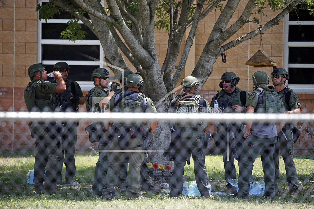 Law enforcement personnel stand outside Robb Elementary School following a shooting, May 24, 2022, in Uvalde, Texas. When the gunman arrived at the school, he hopped its fence and easily entered through an unlocked back door, police said. He holed himself up in a fourth-grade classroom where he killed the children and teachers. (AP Photo/Dario Lopez-Mills, File)