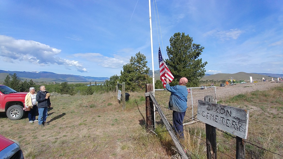 Plains veteran Ole Oleschlager hoists the Stars and Stripes as volunteers stand with their hands over their heart at the beginning of a spruce up mission at the Dixon Cemetery just north of the town of Dixon.  (Chuck Bandel/VP-MI)