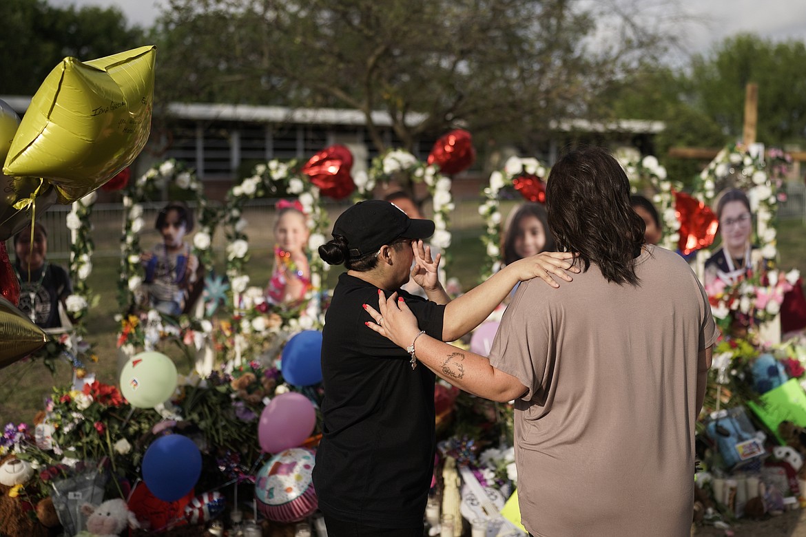 Jolean Olvedo, left, wipes her tears while being comforted by her partner Natalia Gutierrez at a memorial for Robb Elementary School students and teachers who were killed in last week's school shooting in Uvalde, Texas, Tuesday, May 31, 2022. (AP Photo/Jae C. Hong)