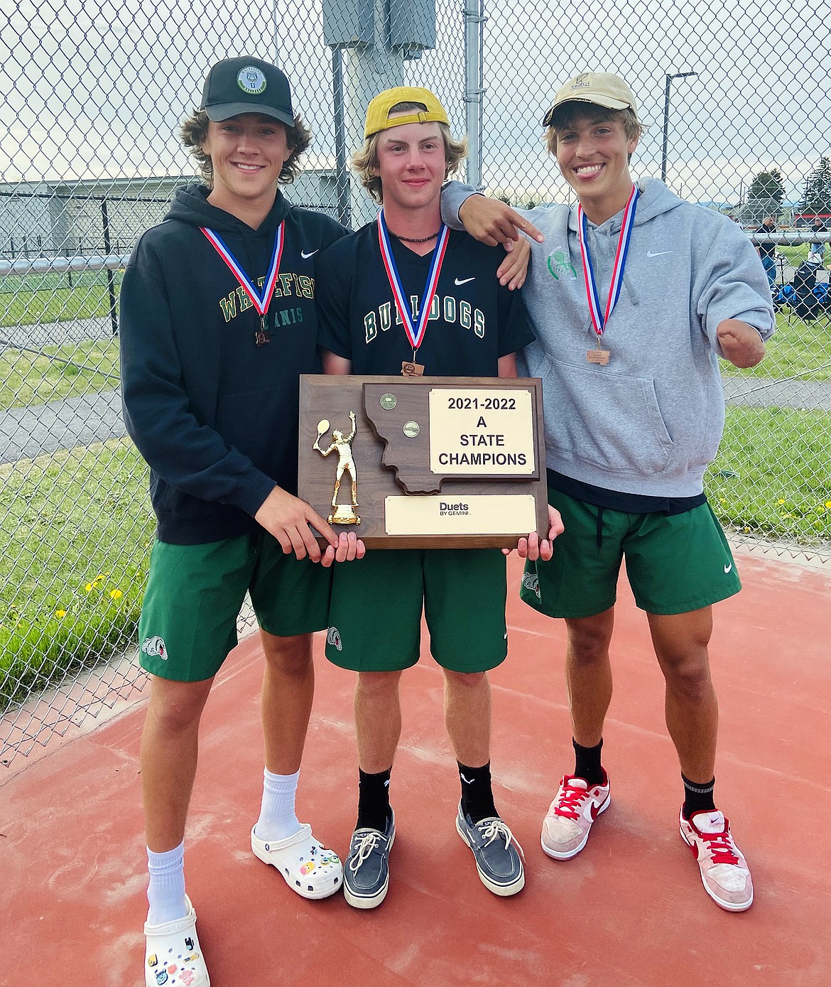 Bulldogs Mason Kelch, Aaron Dicks and Joe Brandt hold the State A Championship trophy after winning the state team title in Bozeman on Friday. (Courtesy photo)