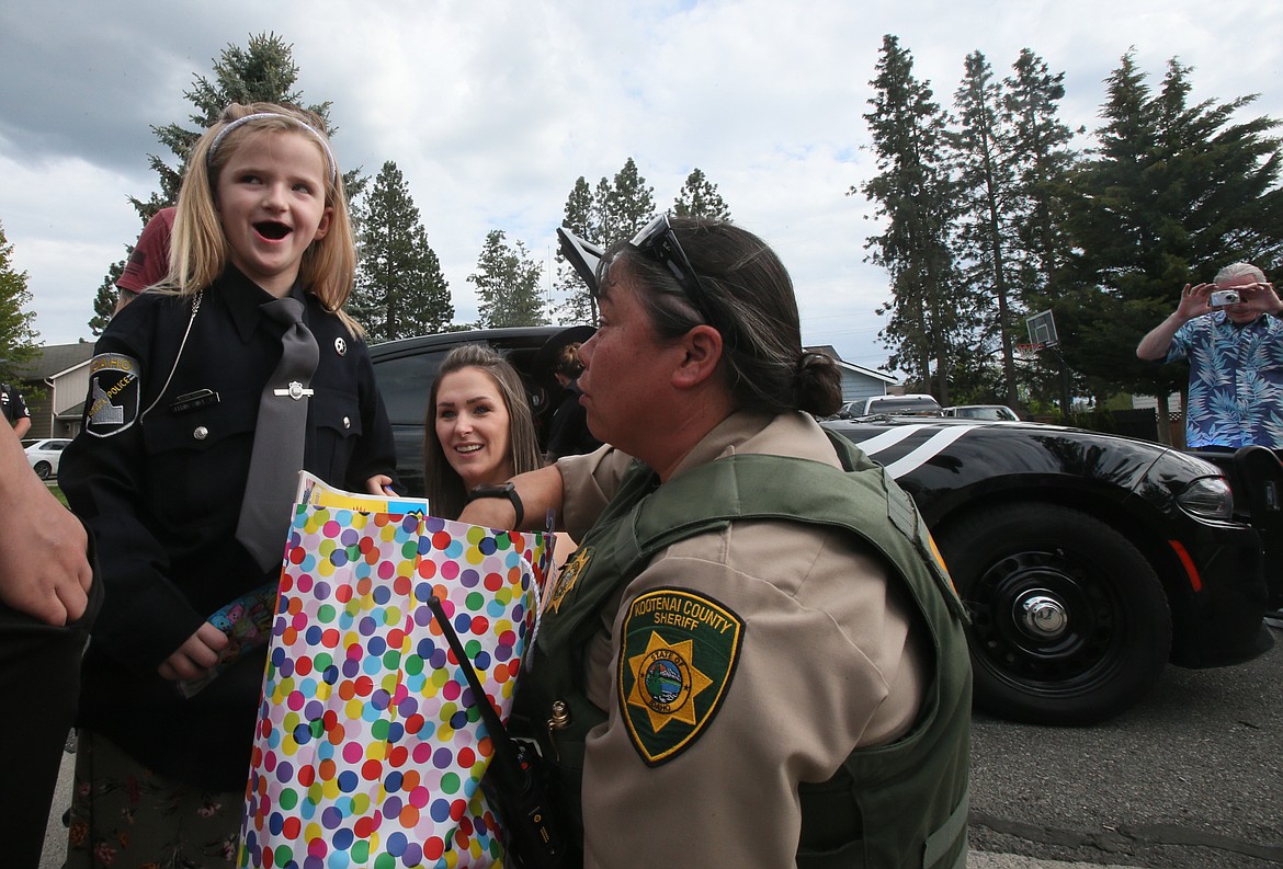 In her new Idaho State Police jacket, honorary trooper Jaicey Lupton, 7, is delighted by a goodie bag presented by Kootenai County Sheriff's Office Deputy sheriff Alana Hunt.