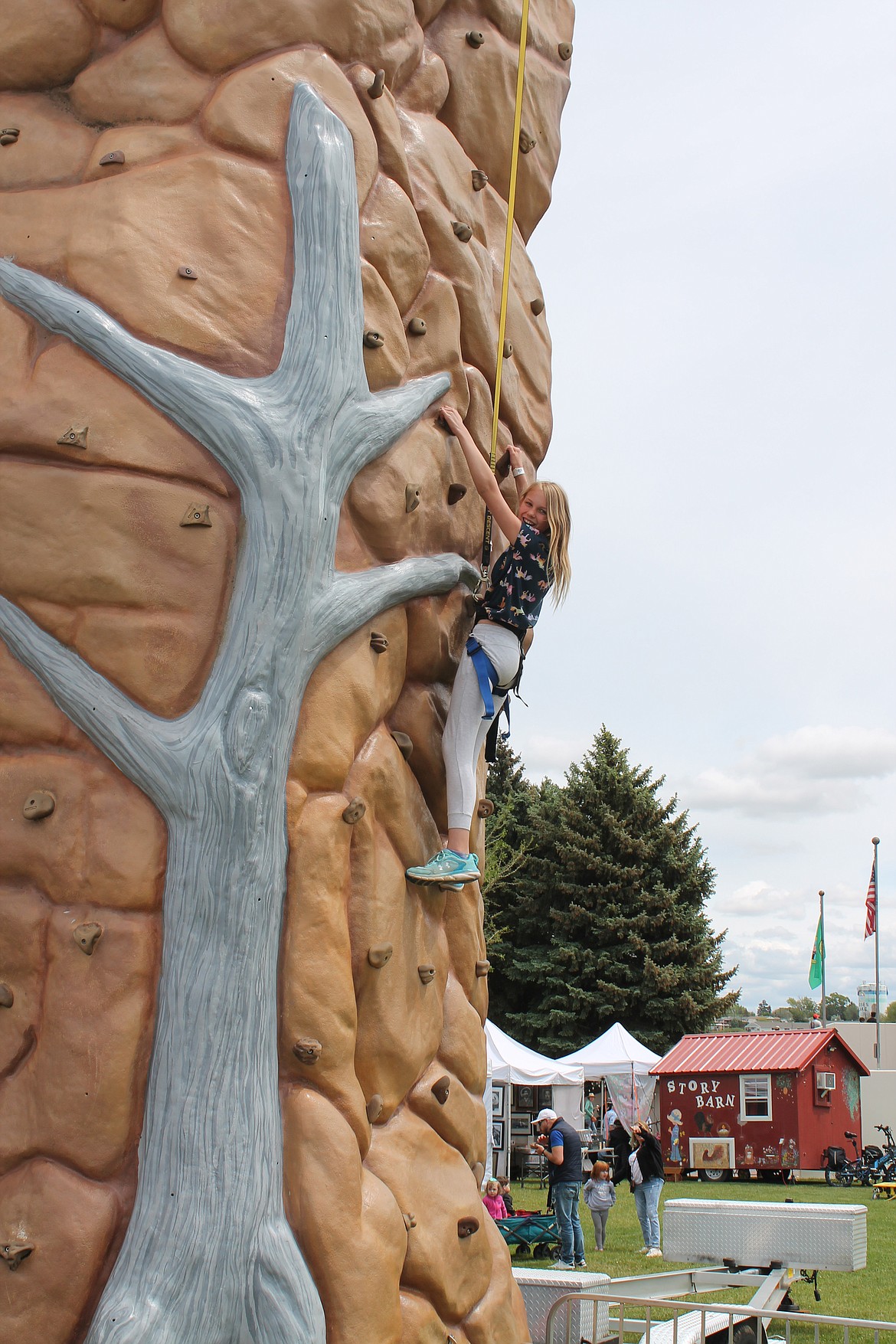 Ten-year-old Melanie Macomber of Moses Lake glances down to her parents for support as she makes her way up the rock-climbing wall Saturday. The attraction was part of the Moses Lake Spring Festival.