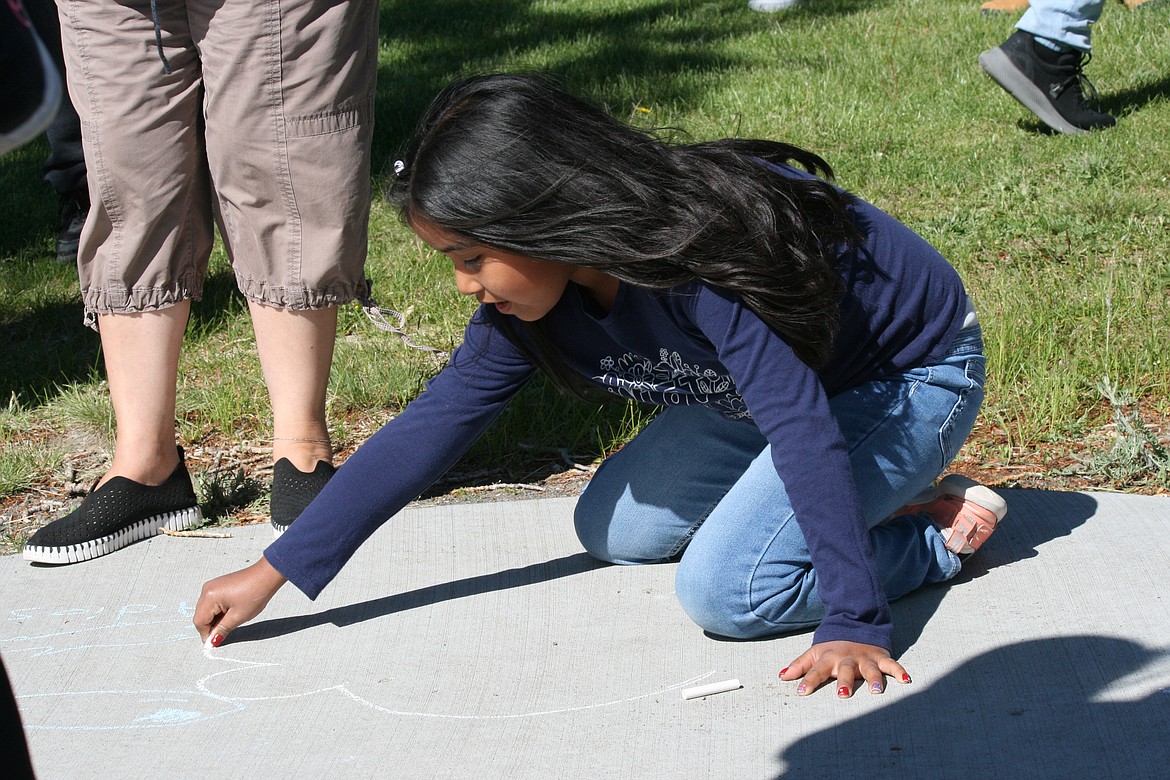 Chelsy Aruajo draws a fish on the sidewalk at Desert Aire Park during the salmon release party for Wahluke elementary students.