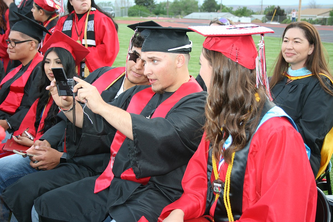 Othello High School graduates do some livestreaming during Friday’s ceremony.