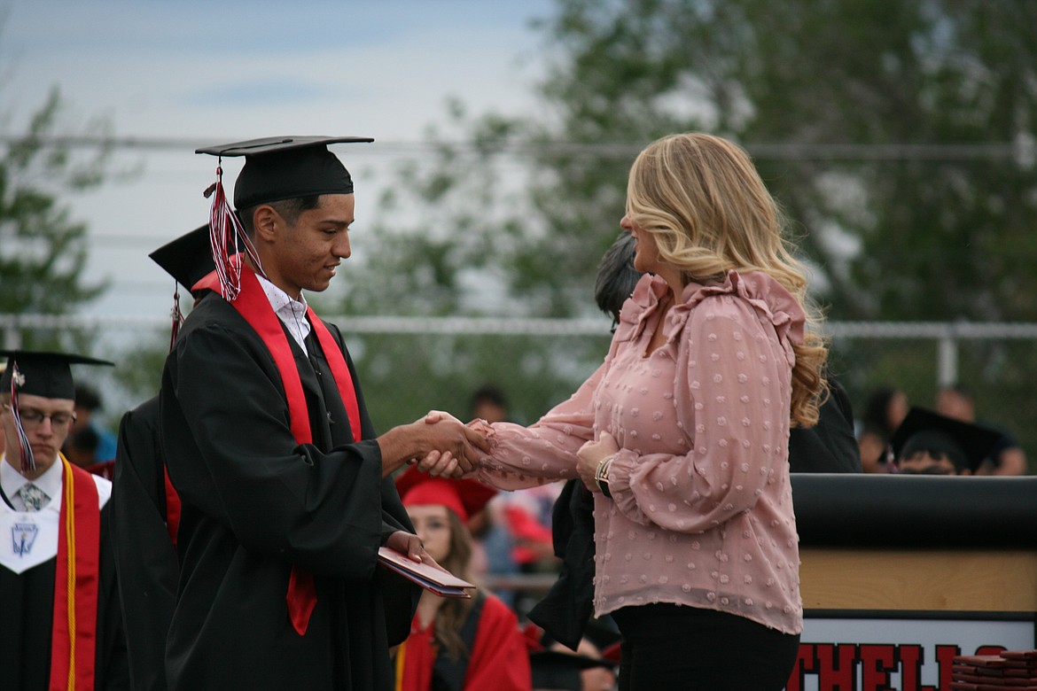 An Othello senior receives his diploma from Othello School Board member Lindsy Prows during graduation ceremonies Friday.