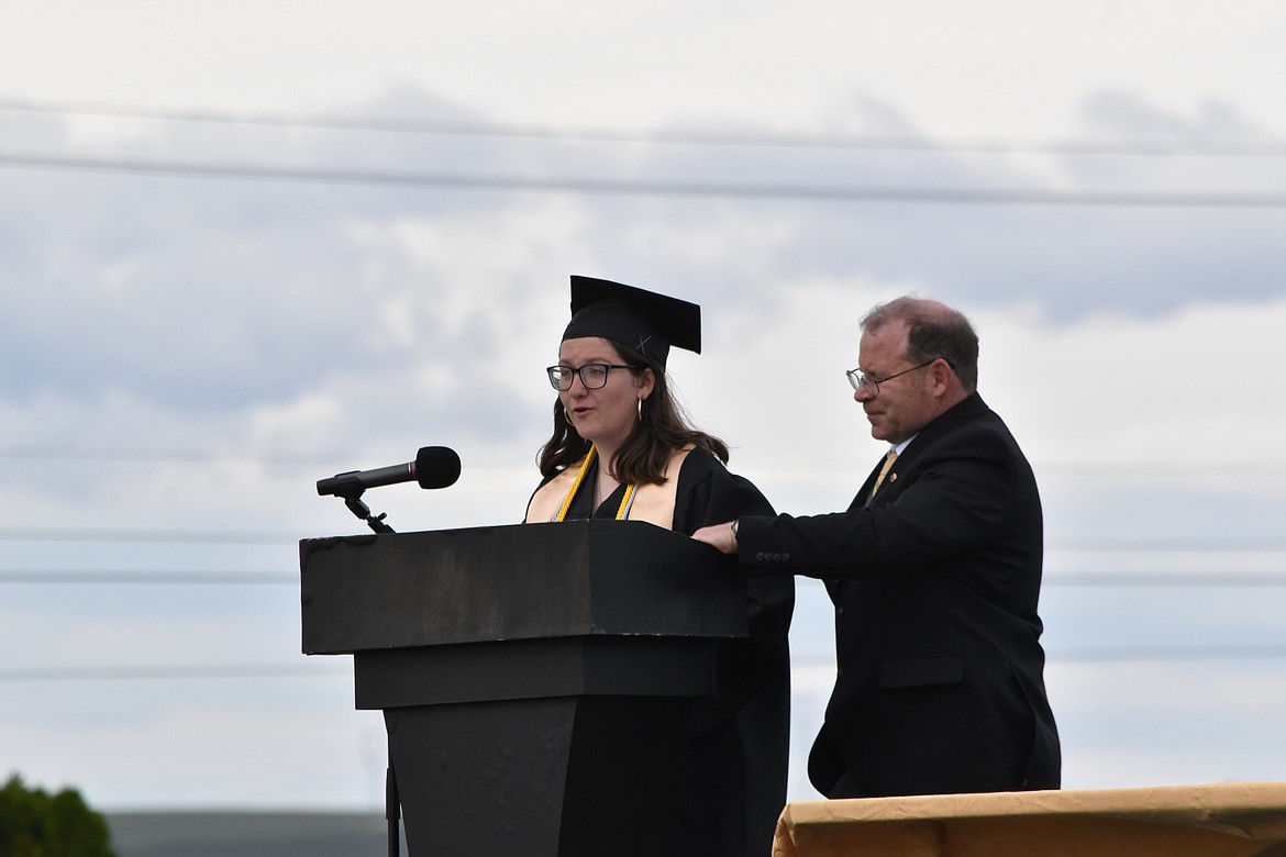 Class speaker Bryn Christiensen addresses her class as Assistant Principal Randy Miller holds her speech for her because of the slight breeze.