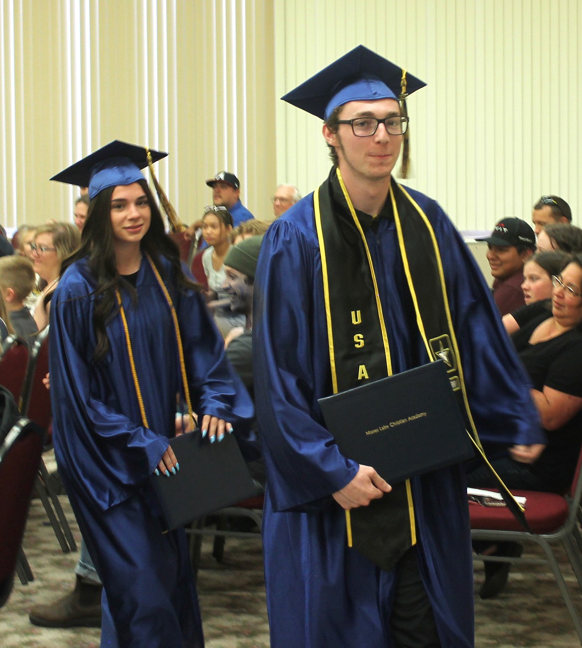 Newly-minted MLCA graduates Aspen Merkle, left, and Christian Hoefler leave the chapel with their diplomas Saturday. Merkle plans to continue her education at Big Bend Community College and Hoefler intends to enter the Army, according to the graduation program.