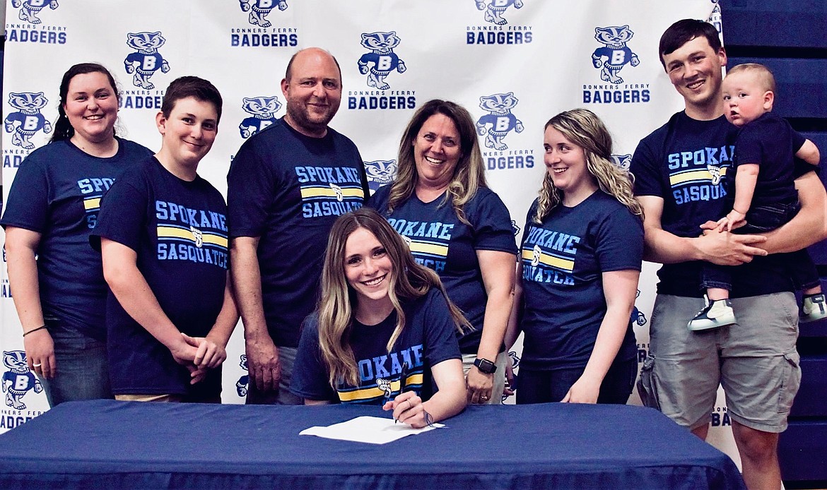 (sitting) Morgan Burt signs for to join the pole vaulting team at Spokane Falls Community College with her family.