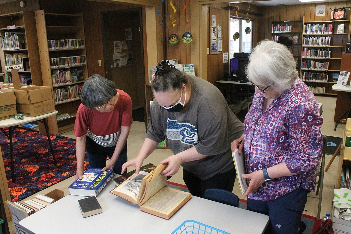 Warden Friends of the Library president Toshi Nitta, left, and volunteer Patty Erickson, right, look over some of the books Christina Calzacorta, center, found at the book sale Thursday. Calzacorte ended up with four boxes of books plus a few extra.