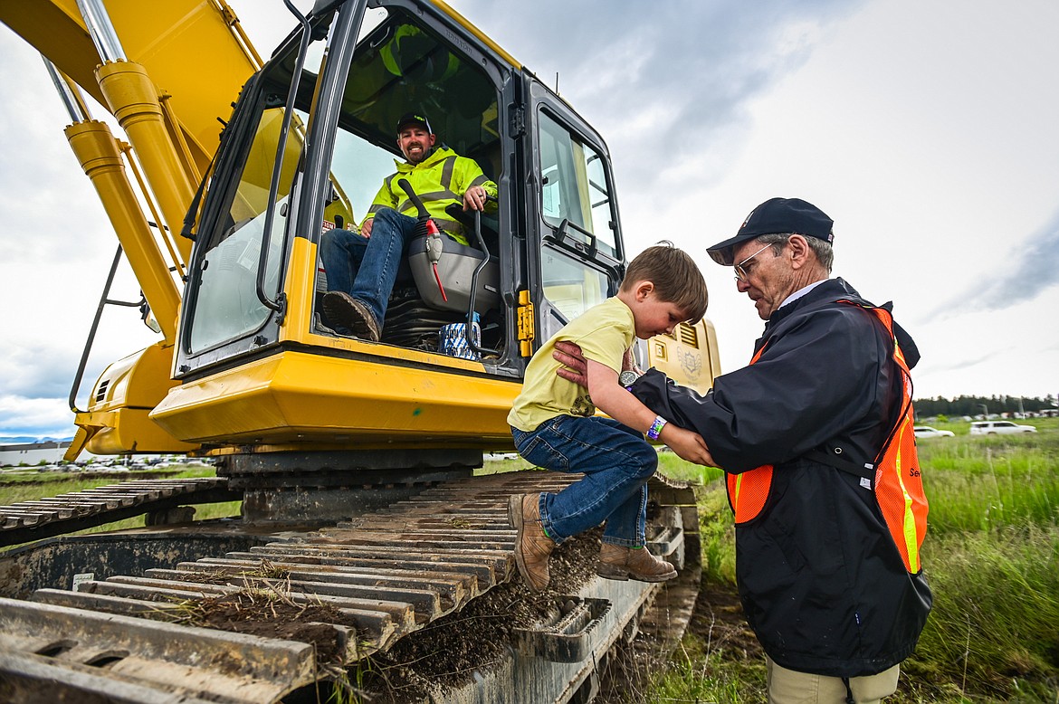 Monte Eliason, right, with the Kalispell Noon Rotary Club, helps Nehemiah Edwards out of an excavator operated by Taylor Quiram at the DIG Rotary event held by Kalispell Daybreak and Noon Rotary Clubs and LHC at the Kalispell North Town Center on Highway 93 and Rose Crossing on Saturday, June 11. Attendees got the opportunity to operate excavators, bulldozers and graders with proceeds going toward the creation of a Splash Pad full of sprayers, showers and water features along the Kalispell Parkline Trail. (Casey Kreider/Daily Inter Lake)