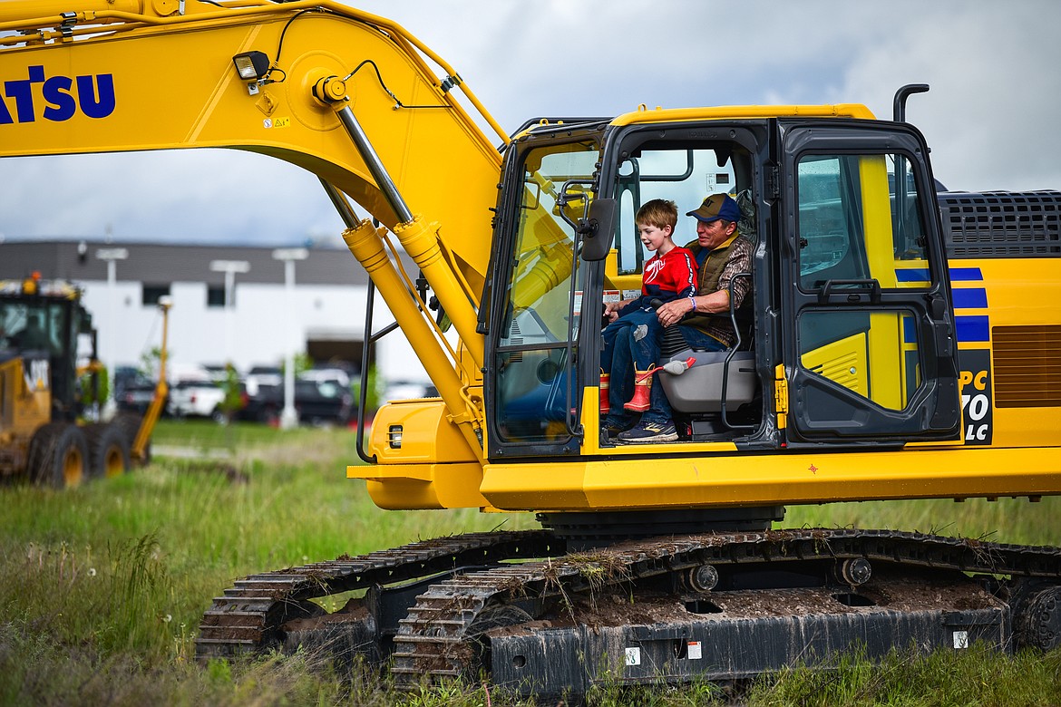 Liam Kates works inside an excavator with Bruce Roberts at the DIG Rotary event held by Kalispell Daybreak and Noon Rotary Clubs and LHC at the Kalispell North Town Center on Highway 93 and Rose Crossing on Saturday, June 11. Attendees got the opportunity to operate excavators, bulldozers and graders with proceeds going toward the creation of a Splash Pad full of sprayers, showers and water features along the Kalispell Parkline Trail. (Casey Kreider/Daily Inter Lake)