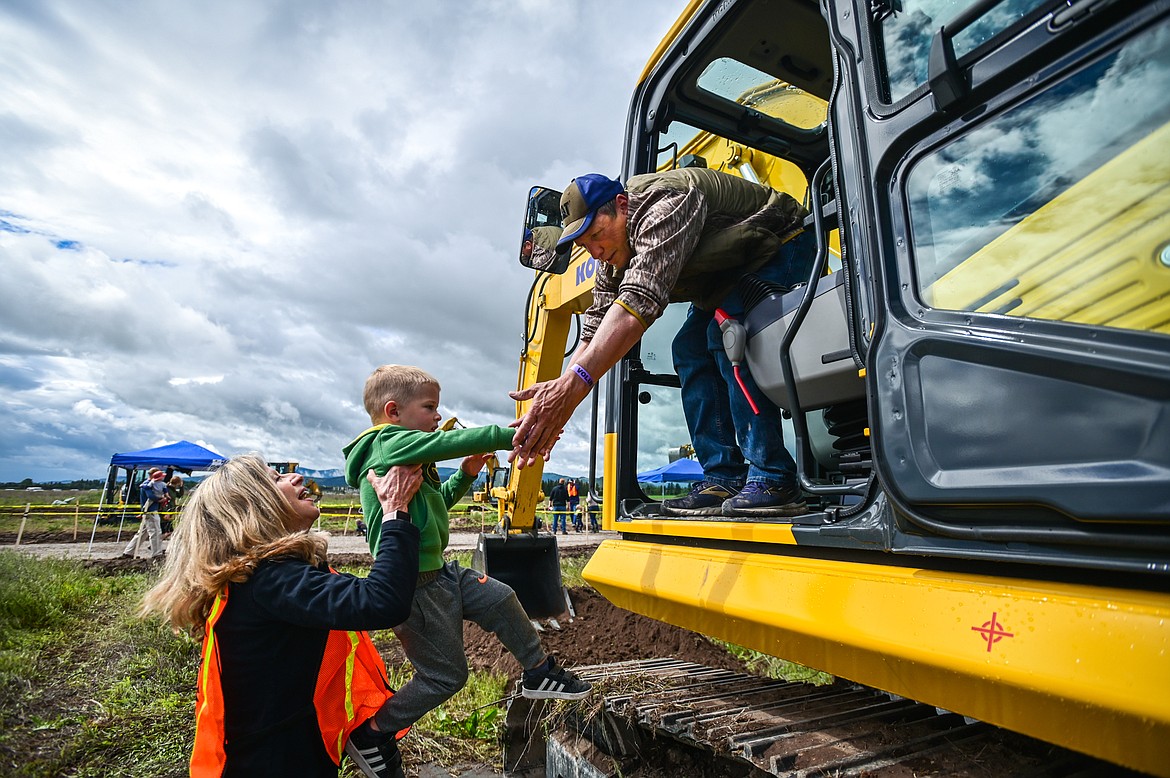 Lucy Smith, left, with the Kalispell Noon Rotary Club, and heavy equipment operator Bruce Roberts help Cannon Dunn, 3, into the cab of an excavator at the DIG Rotary event held by Kalispell Daybreak and Noon Rotary Clubs and LHC at the Kalispell North Town Center on Highway 93 and Rose Crossing on Saturday, June 11. Attendees got the opportunity to operate excavators, bulldozers and graders with proceeds going toward the creation of a Splash Pad full of sprayers, showers and water features along the Kalispell Parkline Trail. (Casey Kreider/Daily Inter Lake)