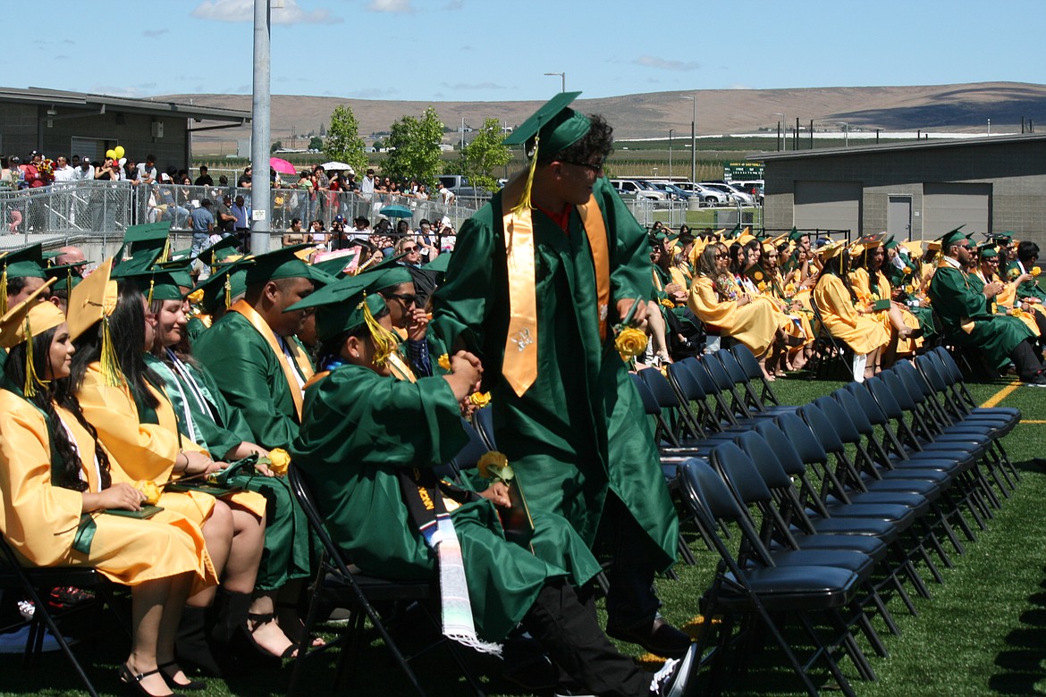 Quincy High School graduates shake hands in congratulation after receiving their diplomas.