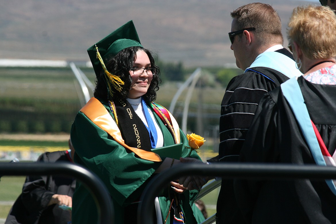 A Quincy graduate smiles with satisfaction while being congratulated on receiving her diploma.