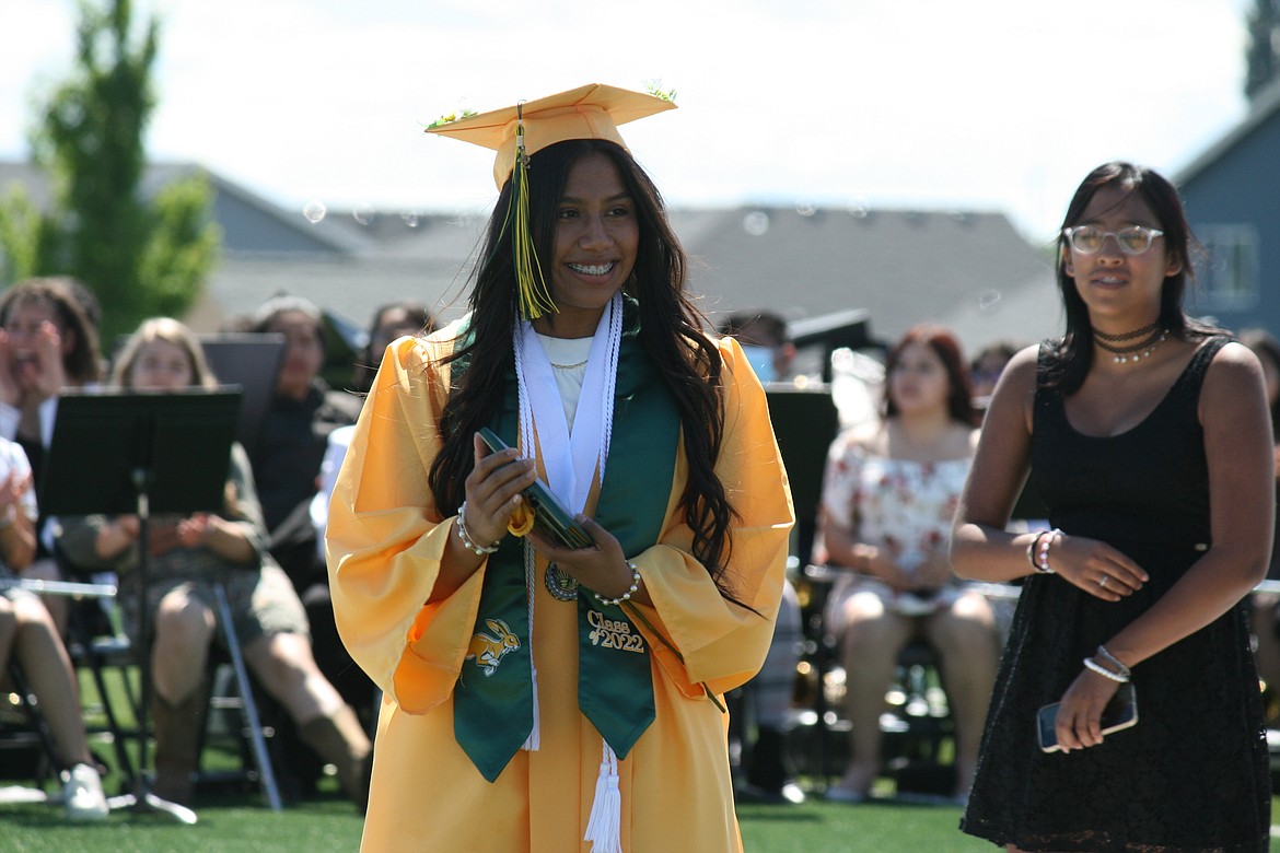 A smiling Quincy High School graduate leaves the stage with her diploma.