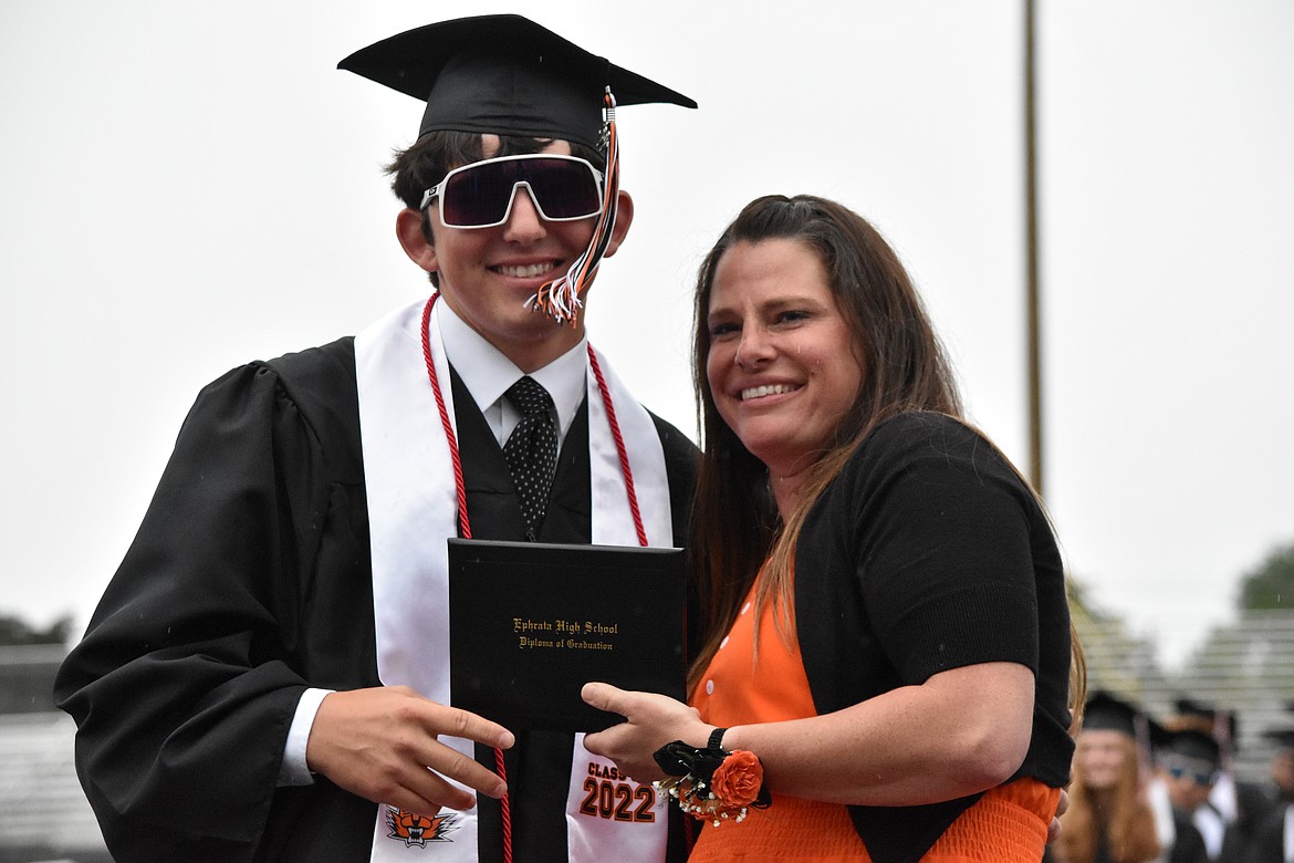 School Board President Alain Black presents her son Ethan with his diploma.