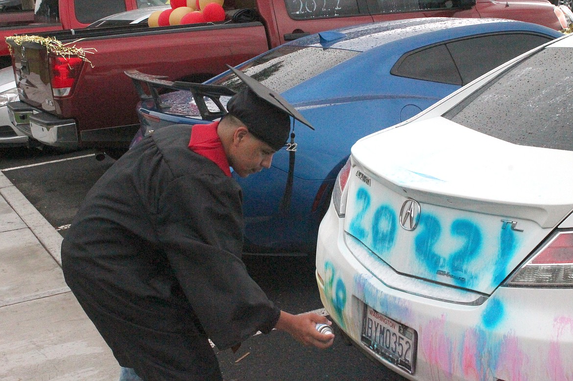 Wahluke High School graduate Irineo Cazares touches up the paint on his car after graduation Friday. The rainy weather had caused his artwork to blur.